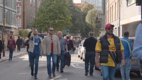 Fans,-Die-Am-Spieltag-Mit-Unterstützern-Durch-Die-Straßen-In-Der-Nähe-Des-Heimstadions-Des-Emirates-Stadions-Arsenal-Football-Club-London-Gehen