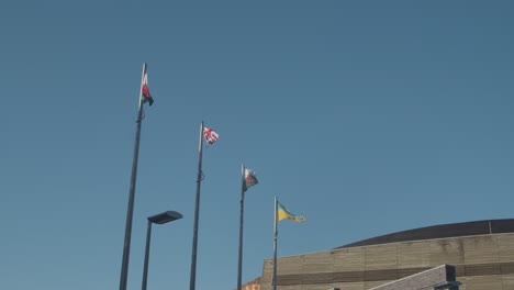 Walisische-Englische-Und-Ukrainische-Flaggen,-Die-Gegen-Den-Blauen-Himmel-Fliegen
