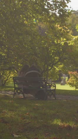 Vertical-Video-Autumn-View-Of-Bute-Park-In-Cardiff-Wales-With-People-Sitting-On-Bench