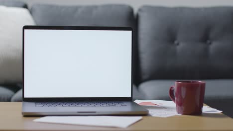 Laptop-With-Blank-Screen-On-Table-At-Home-Covered-With-Bills-In-Cost-Of-Living-Crisis