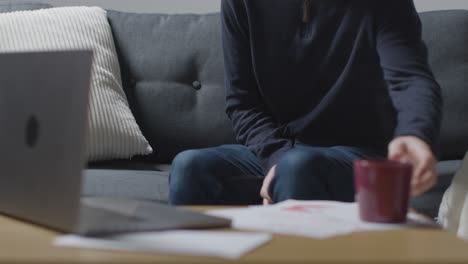 Person-Wearing-Blanket-At-Home-Trying-To-Keep-Warm-With-Laptop-And-Bills-1