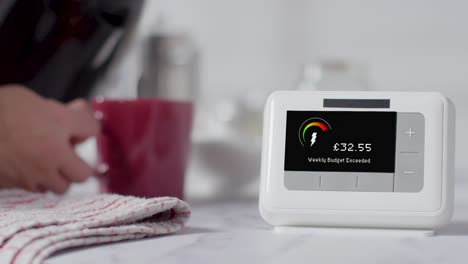 Person,-Die-Zu-Hause-In-Der-Küche-Ein-Heißes-Getränk-Zubereitet,-Mit-Smart-Meter-Im-Vordergrund-1