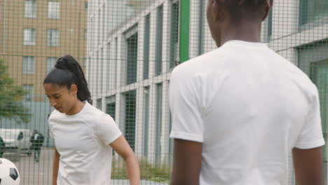 Künstlicher-Fußballplatz-Im-Städtischen-Stadtgebiet-Mit-Jungem-Paar,-Das-Fußball-Tritt-4