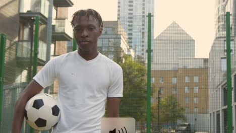 Retrato-De-Un-Joven-Con-Fútbol-Bajo-El-Brazo-En-Un-Campo-De-Fútbol-Artificial-En-El-área-Urbana-De-La-Ciudad