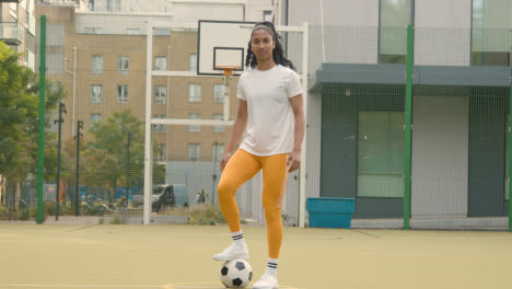 Porträt-Einer-Jungen-Frau-Mit-Fußball-Unter-Dem-Arm-Auf-Einem-Künstlichen-Fußballplatz-Im-Städtischen-Stadtgebiet