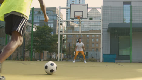 Young-Soccer-Players-Shooting-And-Saving-Shot-On-Goal-On-Artificial-Football-Pitch-In-Urban-City-Area-