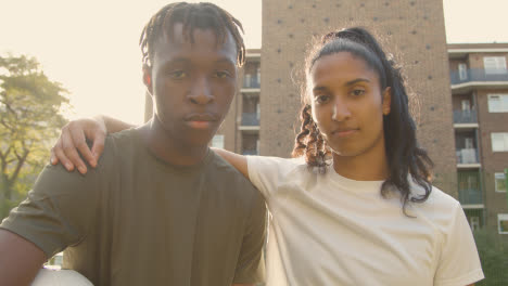 Portrait-Of-Young-Couple-Holding-Football-On-Artificial-Soccer-Pitch-In-Urban-City-Area-1