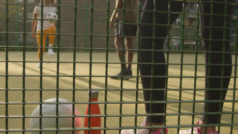 Close-Up-Of-Coach-Watching-Players-Football-Training-On-Artificial-Soccer-Pitch-In-Urban-City-Area-