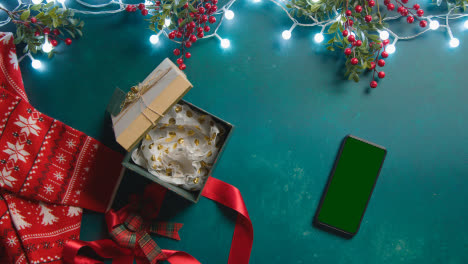 Overhead-Aufnahme-Von-Green-Screen-Handy-Mit-Weihnachtsschmuck-Stechpalmenbeeren-Und-Geschenken