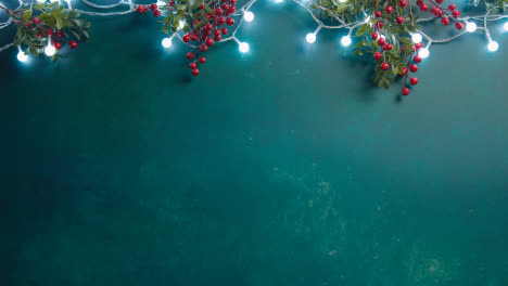Overhead-Shot-Of-Christmas-Lights-With-Berries-On-Green-Background