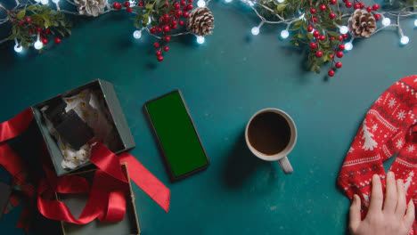 Überkopfaufnahme-Einer-Person-Mit-Heißem-Getränk-Im-Hintergrund-Mit-Weihnachtsschmuck-Und-Geschenken