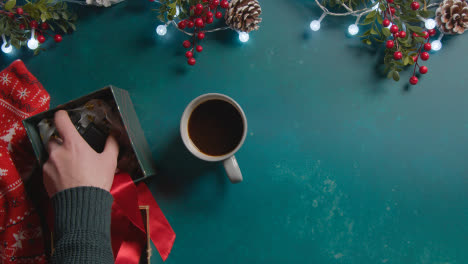 Overhead-Shot-Of-Person-With-Hot-Drink-On-Background-With-Christmas-Decorations-And-Gift-Of-Perfume