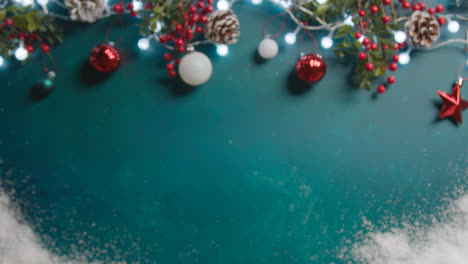 Defocused-Overhead-Shot-Von-Weihnachtsbeleuchtung-Mit-Beeren-Und-Baumschmuck-Auf-Grünem-Hintergrund-Mit-Schnee