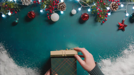 Überkopfaufnahme-Einer-Person,-Die-Ein-In-Geschenk-Verpacktes-Weihnachtsgeschenk-Mit-Festlichem-Hintergrund-öffnet