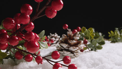 Studio-Christmas-Still-Life-With-Decorations-Berries-And-Pine-Cones-On-Artificial-Snow