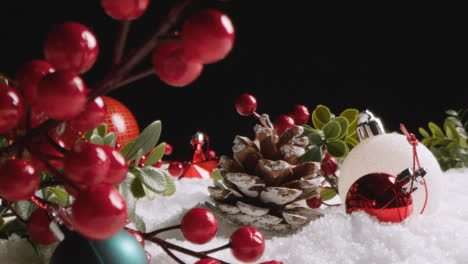 Studio-Christmas-Still-Life-With-Tree-Decorations-Berries-And-Pine-Cones-On-Artificial-Snow