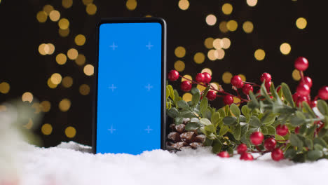 Teléfono-Móvil-De-Pantalla-Azul-Sobre-Fondo-De-Navidad-Con-Nieve-Y-Follaje-2