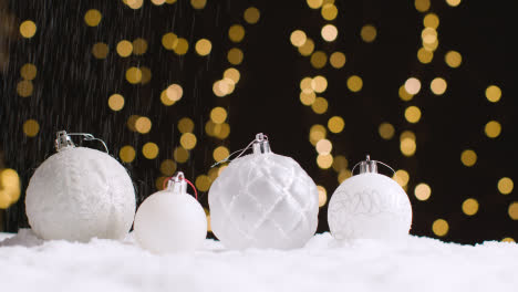 Studio-Weihnachtsstilleben-Mit-Schnee,-Der-Auf-Dekorationen-Mit-Lichtern-Im-Hintergrund-Fällt-1