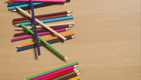 Mehrfarbige-Bleistifte,-Die-Den-Hölzernen-Hintergrund-Herunterrollen-3