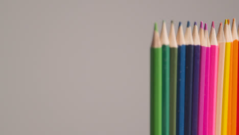 Studio-Shot-Of-Rotating-Line-Of-Multi-Coloured-Pencils-Against-Grey-Background-1