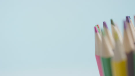 Studio-Shot-Of-Rotating-Multi-Coloured-Pencils-Against-Blue-Background-1