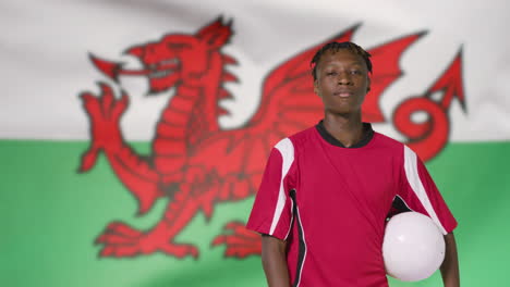 Junger-Fußballer,-Der-Vor-Der-Wales-flagge-Zur-Kamera-Geht-01