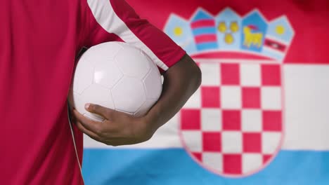 Joven-Futbolista-Caminando-Sosteniendo-El-Fútbol-Frente-A-La-Bandera-De-Croacia