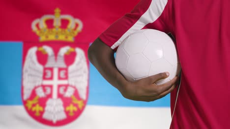Junger-Fußballer,-Der-Fußball-Vor-Serbien-flagge-Hält