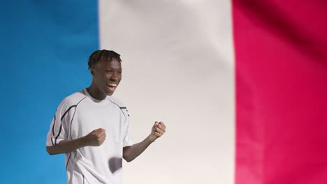 Junger-Fußballer,-Der-Vor-Der-Französischen-Flagge-Vor-Der-Kamera-Feiert
