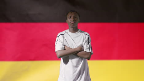 Joven-Futbolista-Posando-Frente-A-La-Bandera-De-Alemania