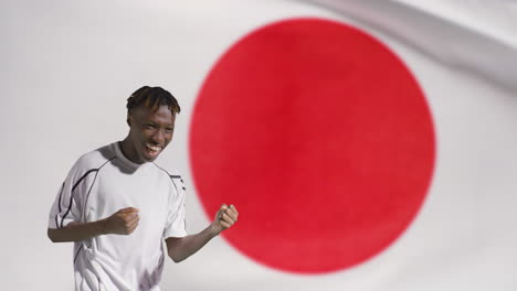 Junger-Fußballer,-Der-Vor-Der-Japanischen-Flagge-Vor-Der-Kamera-Feiert