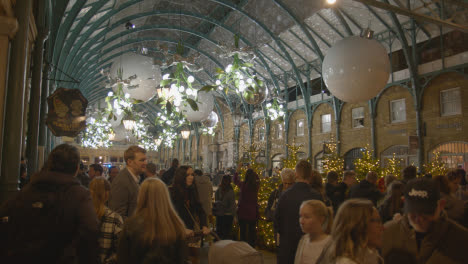 Luces-Y-Decoraciones-Navideñas-Con-Compradores-En-Covent-Garden,-Londres,-Reino-Unido-Por-La-Noche