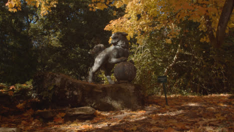 Sculpture-Of-Chinese-Dragon-Dog-In-Arboretum-With-Colourful-Autumn-Trees-In-Background