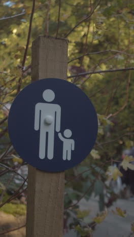 Vertikales-Video-Von-Schildern,-Die-Eltern-Mit-Kindern-Auf-Einer-Brücke-Im-Arboretum-Warnen