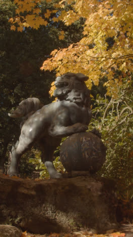 Video-Vertical-De-La-Escultura-Del-Perro-Dragón-Chino-En-El-Arboreto-Con-Coloridos-árboles-De-Otoño-En-El-Fondo