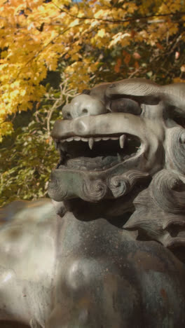 Vertikales-Video-Der-Skulptur-Des-Chinesischen-Drachenhundes-Im-Arboretum-Mit-Bunten-Herbstbäumen-Im-Hintergrund