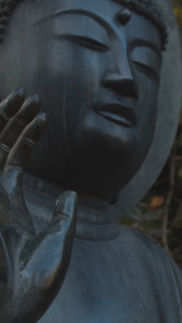 Vertical-Video-Close-Up-Of-Sculpture-Of-Buddha-In-Arboretum