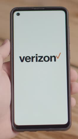 Vertical-Video-Of-Hand-Holding-Mobile-Phone-With-Screen-Showing-Brand-Logos-For-Tencent,Verizon,AT&T,Spectrum,Xfinity-and-Apple