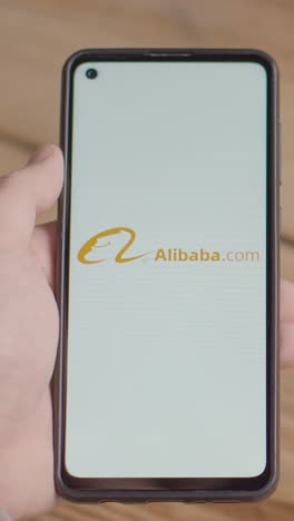 Video-Vertical-De-La-Mano-Sosteniendo-Un-Teléfono-Móvil-Con-Una-Pantalla-Que-Muestra-Logotipos-De-Marca-Para-Tik-Tok,-Alibaba,-Coca-Cola,-Meta-Y-Starbucks