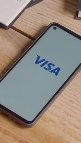 Video-Vertical-De-Teléfono-Móvil-Con-Pantalla-En-El-Escritorio-Que-Muestra-Logotipos-De-Marca-Para-Qualcomm,visa,-Mastercard,-American-Express-Y-Paypal