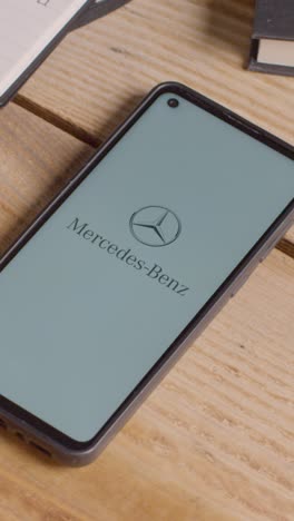 Video-Vertical-De-Un-Teléfono-Móvil-En-El-Escritorio-Con-Una-Pantalla-Que-Muestra-Logotipos-De-Marca-Para-Tesla,-Mercedes-Benz,-Bmw-Y-Toyota