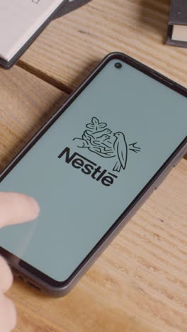 Vertikales-Video-Eines-Mobiltelefons-Auf-Dem-Schreibtisch-Mit-Bildschirm-Mit-Markenlogos-Für-Mcdonalds,-Nestle,-Coca-Cola,-Starbucks-Und-Pepsico