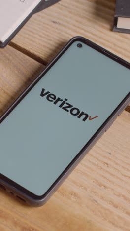 Video-Vertical-De-Un-Teléfono-Móvil-En-El-Escritorio-Con-Una-Pantalla-Que-Muestra-Los-Logotipos-De-Marca-Para-Tencent,verizon,at