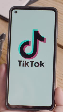 Vertical-Video-Of-Hand-Holding-Mobile-Phone-With-Screen-Showing-Brand-Logos-For-Google,Tik-Tok,Meta,Facebook,Instagram,Netflix,YouTube-And-Tencent