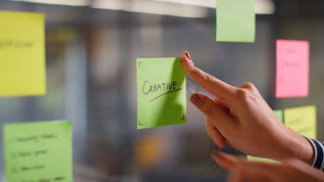 Close-Up-Of-Woman-Putting-Sticky-Note-With-Creative-Written-On-It-Onto-Transparent-Screen-In-Office-2