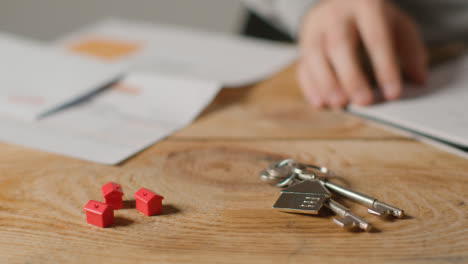 Hauskaufkonzept-Mit-Schlüsseln-Am-Hausförmigen-Schlüsselring-Und-Person,-Die-Finanzen-überprüft-4