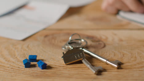 Hauskaufkonzept-Mit-Schlüsseln-Am-Hausförmigen-Schlüsselring-Und-Person,-Die-Die-Finanzen-überprüft-7