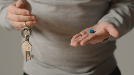 Hauskaufkonzept-Mit-Person,-Die-Schlüssel-Auf-Hausförmigem-Schlüsselring-Und-Blauem-Vorbildhaus-Hält
