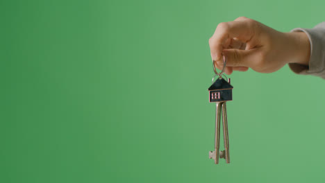 Hauskaufkonzept-Mit-Person,-Die-Schlüssel-Auf-Hausförmigem-Schlüsselring-Vor-Grünem-Bildschirmhintergrund-Hält