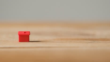 Home-Buying-Concept-With-Red-Plastic-Model-Of-House-On-Wooden-Surface